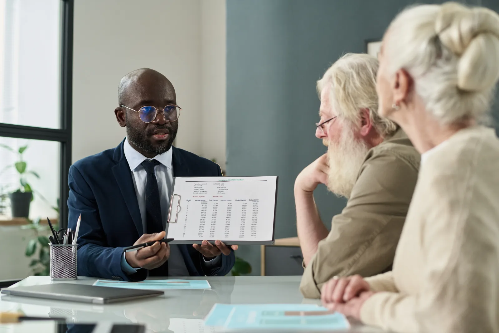 A wealth preservation advisor presenting a protection plan chart to clients during a review meeting.